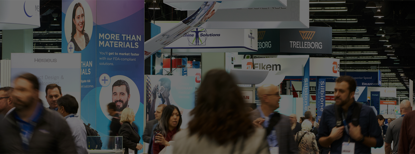Wide shot of exhibitor booths and attendees walking by