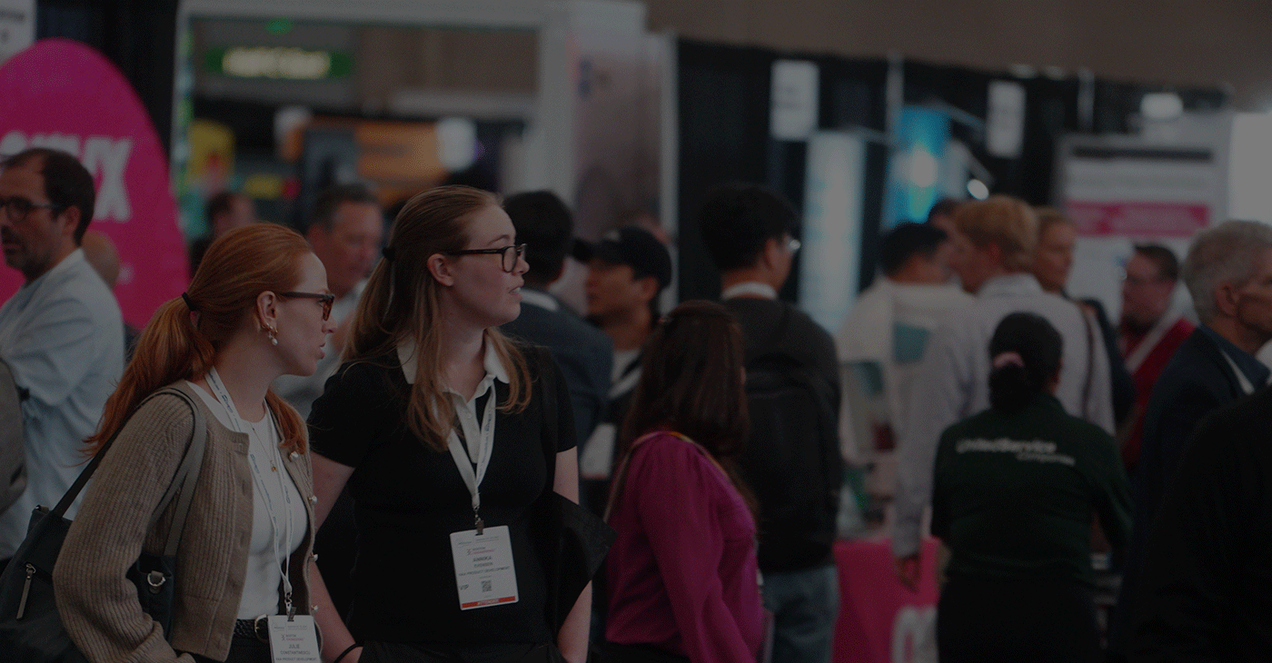 Two women having a conversation in a crowded expo hall