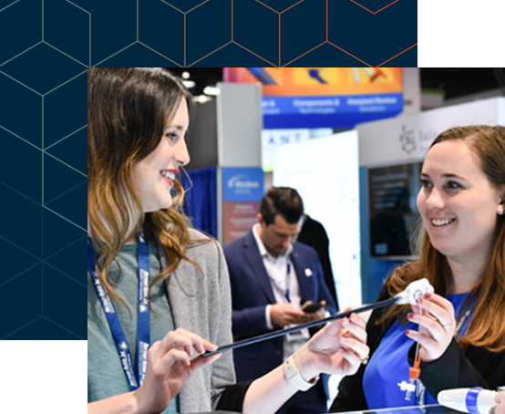 Two women smiling at one another while looking at a product photo